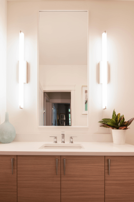 A bathroom vanity with lighting fixtures on both sides of the mirror