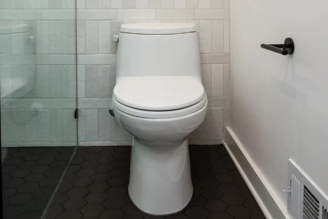 A modern white toilet in a recently remodeled bathroom by Ranney Blair