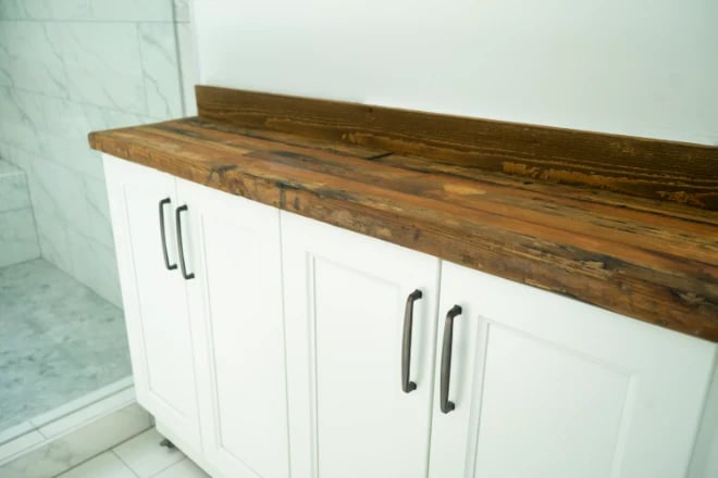 A white bathroom cabinet with a natural wood countertop