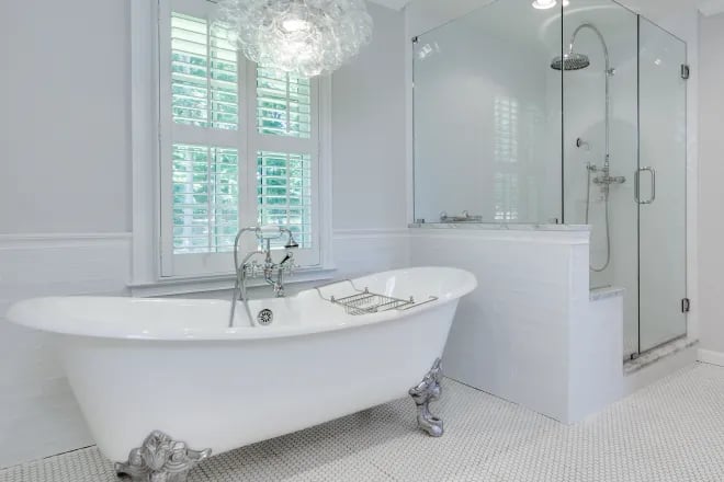 An antique-style freestanding tub next to a glass-enclosed shower in a bathroom remodel done by Ranney Blair