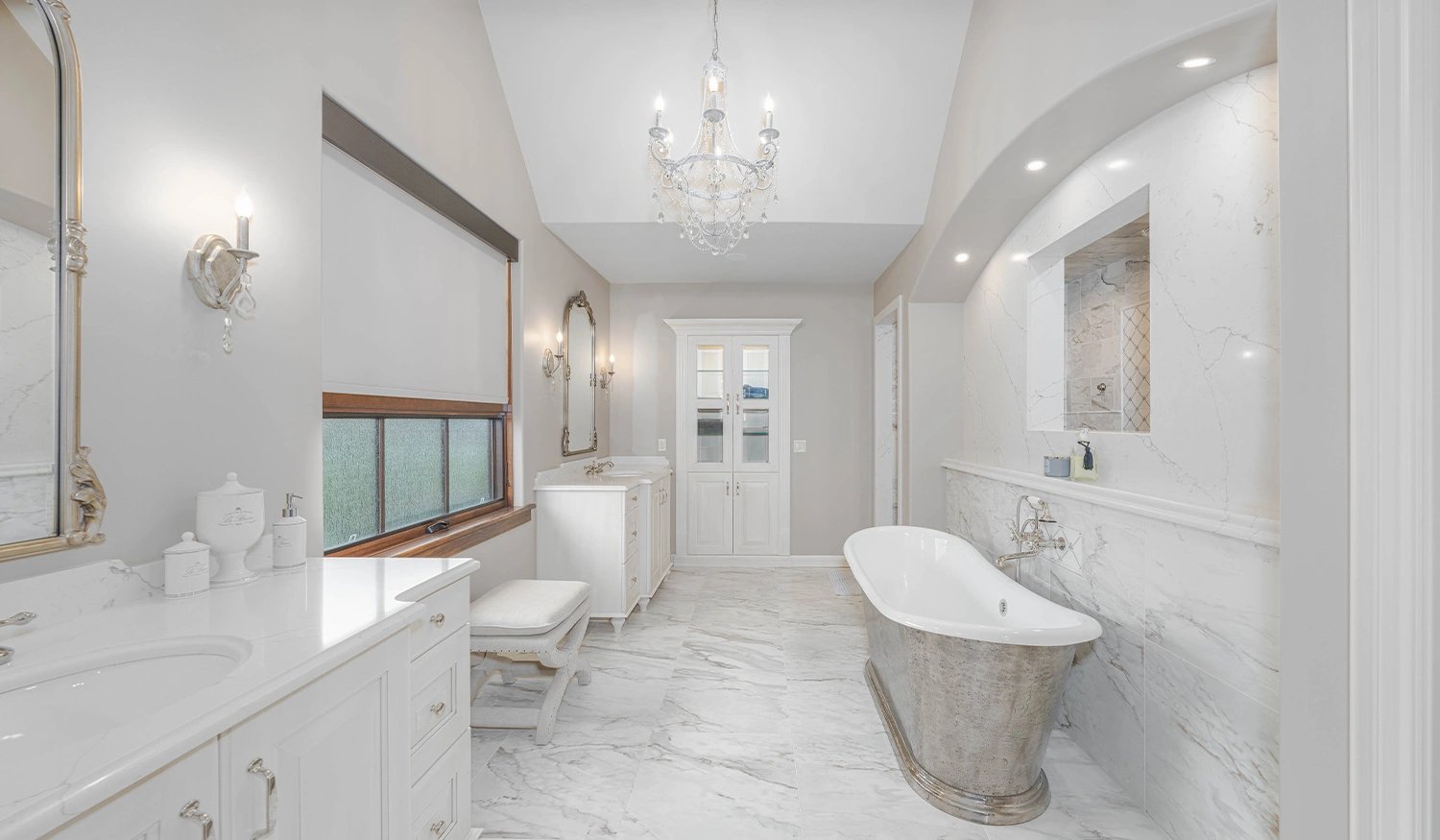A remodeled bathroom with luxurious finishes, including marble tile and a natural stone bathtub.