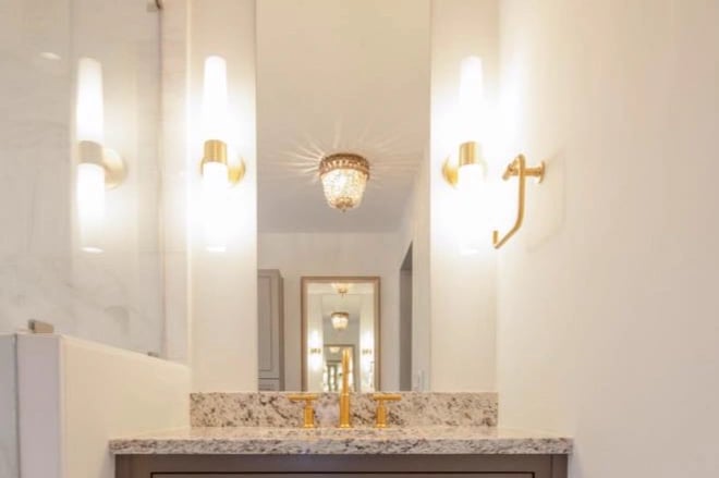 Two wall sconces with a ceiling light visible in the mirror