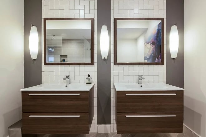 Wall mounted lights in a bathroom next to the mirrors
