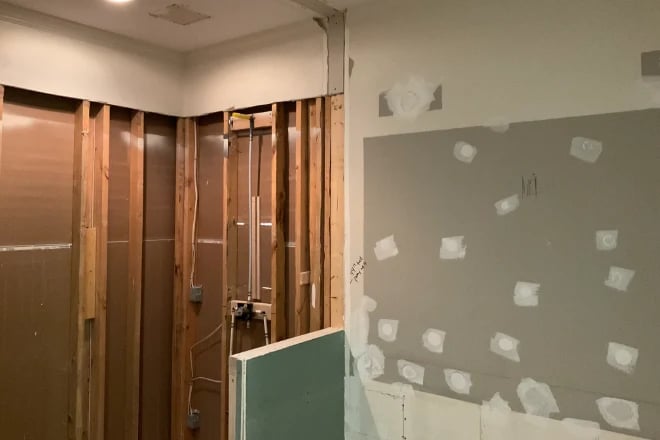 A bathroom remodel with the bare walls exposed and repairs to the wall surface underway