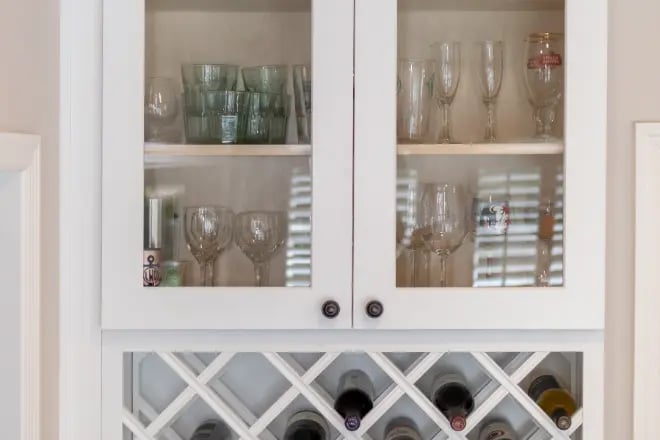 A cabinet with a glass door and a wine rack underneath it