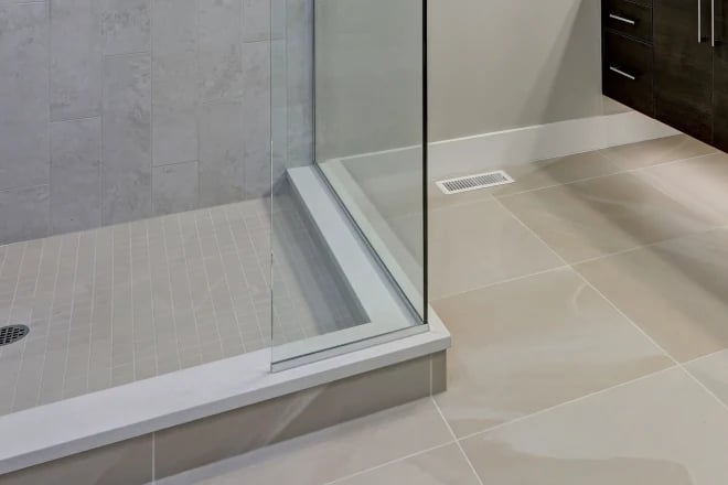 A close up of a glass shower enclosure corner that is utilizing U-channel supports