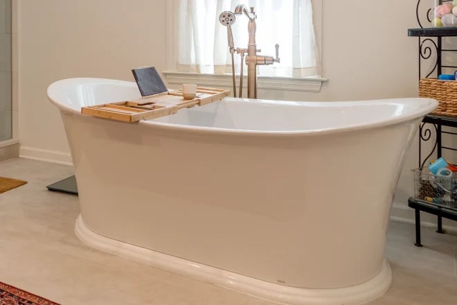 A deep soaker tub in a bathroom, in front of a window