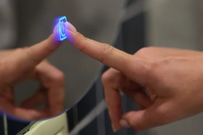 A hand pushing a luminous button on a smart mirror