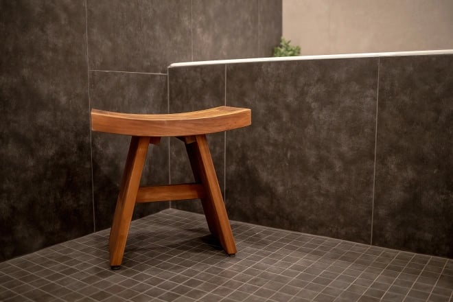 A luxury bathroom remodel with multiple types of tile and a small wooden stool in the foreground