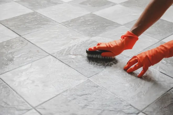 A person scrubbing a tile floor by hand