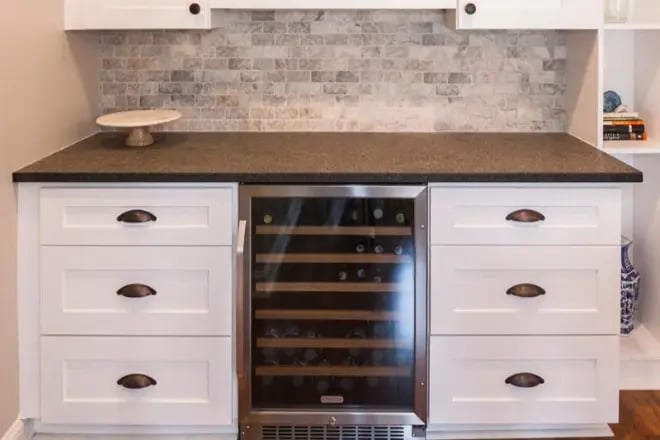A wine cooler integrated in cabinetry with countertop space above
