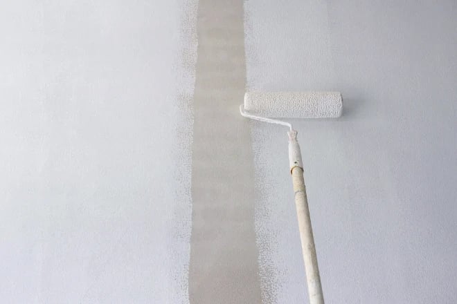 Long handle roller brush applying primer white paint