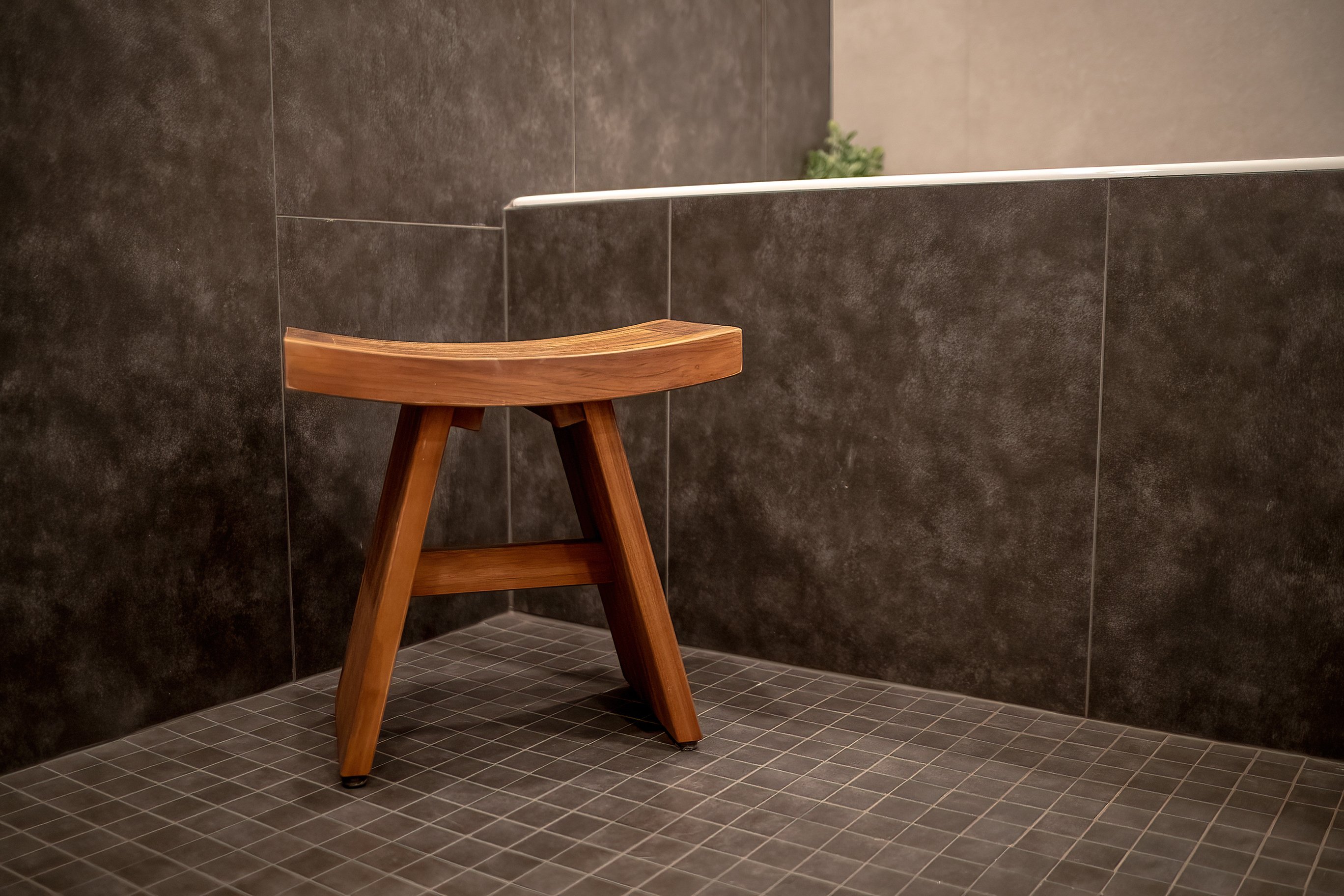 A luxury bathroom remodel with multiple types of tile and a small wooden stool in the foreground