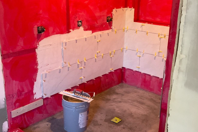 A tile installation underway in a a shower with the backer board visible