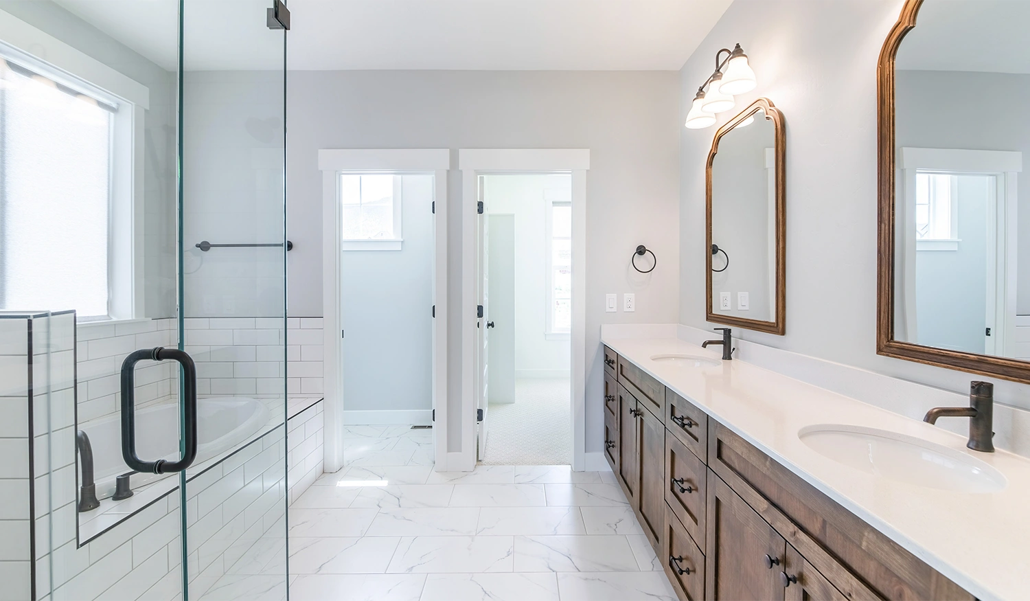 A remodeled bathroom featuring white floor tiles, a double sink vanity, and a bathtub.