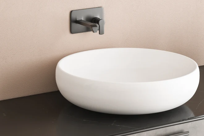 white sink with oval mirror standing on marble countertop in modern bathroom with beige walls
