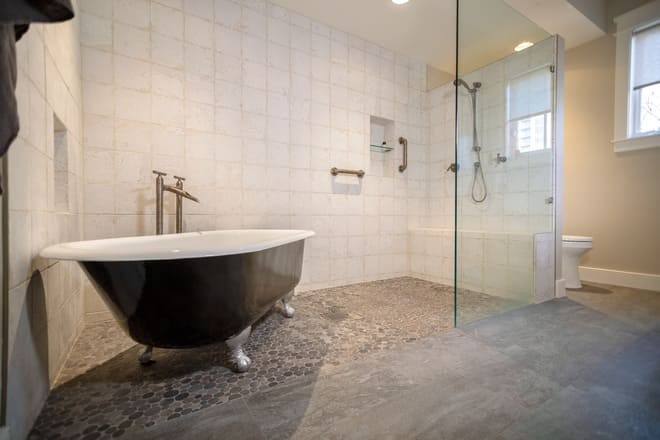 A remodeled bathroom featuring a zero curb shower and natural stone tile